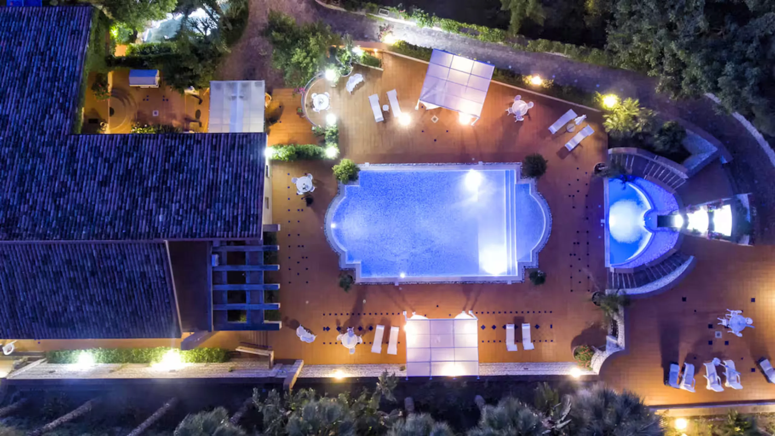The terrace and the lit pool after dark, from above
